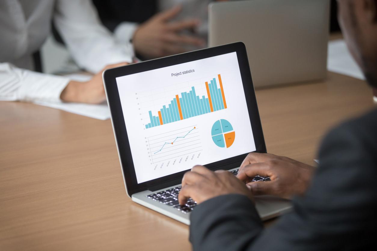 Businessman working on computer analyzing project statistics on screen