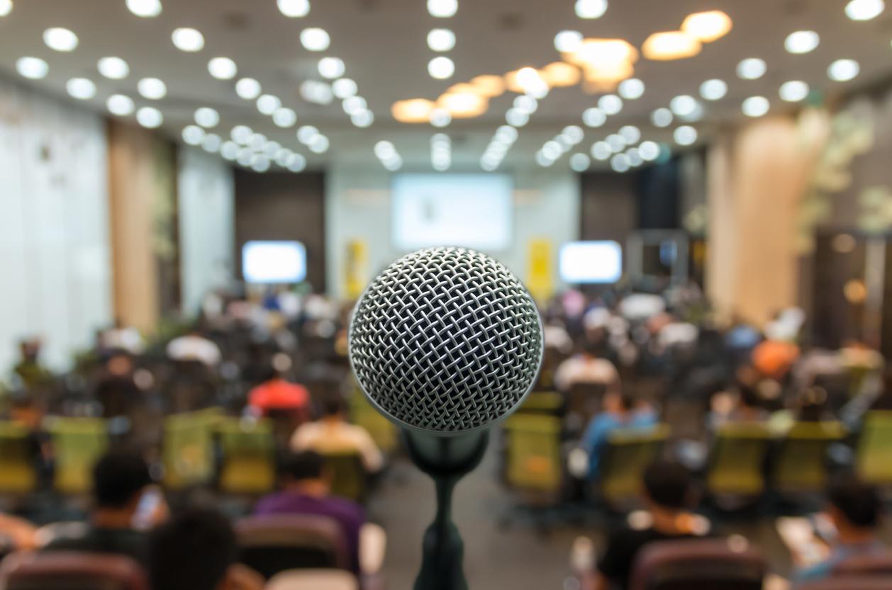 To show an available microphone in front of an audience to tell a story to