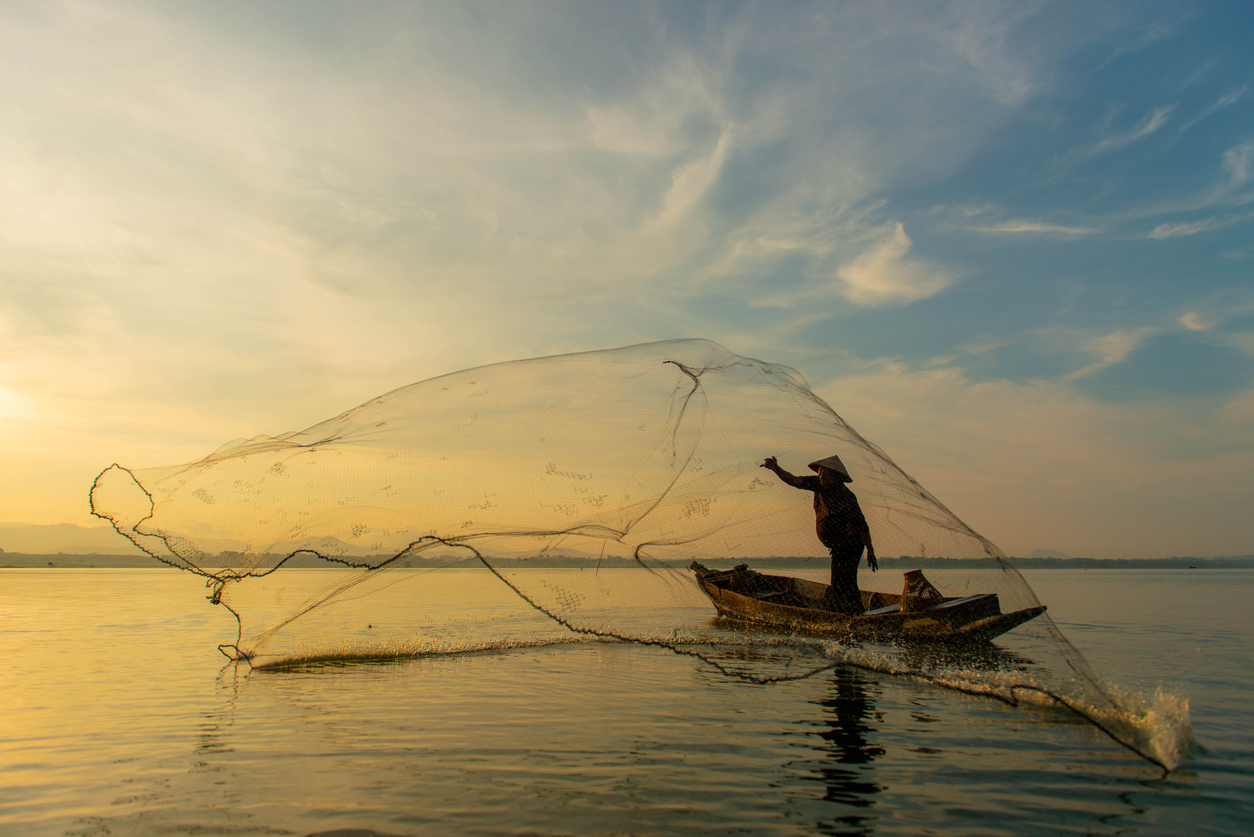 Silhouette Fisherman throwing a castnet into the water