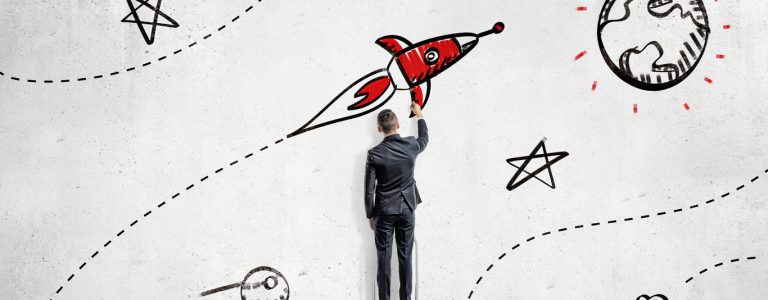 A businessman draws paints a rocket that will reach a goal set on a planet's surface. High aspirations. Business planning. Life and business goals.